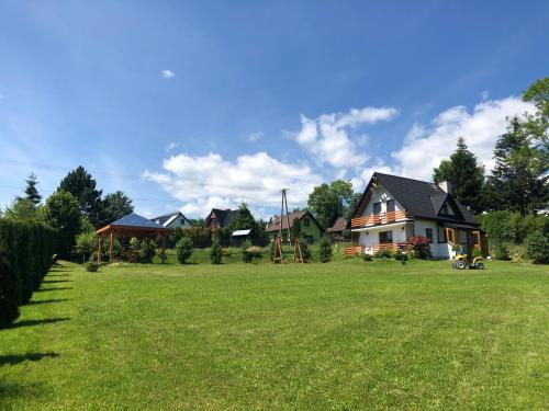 a large yard with a house in the background at Domek Letniskowy in Zubrzyca Dolna