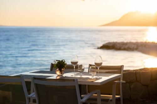 a table with wine glasses on the beach at Bluesun hotel Berulia in Brela