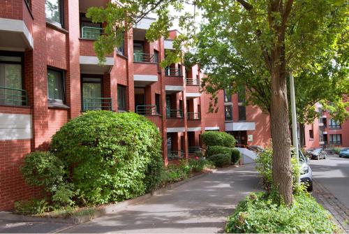 a red brick apartment building with a tree and bushes at Tante ALMA's Bonner Hotel in Bonn