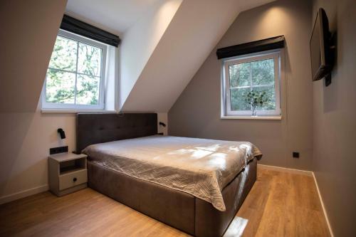 ein Schlafzimmer mit einem Bett und zwei Fenstern in der Unterkunft Apartment Austėja in Karklė