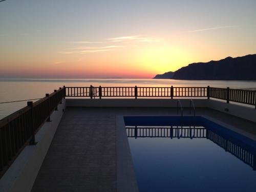 a swimming pool with the sunset in the background at Anemos-Halcyon-Eirene in Mochlos