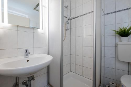 La salle de bains blanche est pourvue d'un lavabo et d'une douche. dans l'établissement Ferienwohnung res publica, à Wuppertal