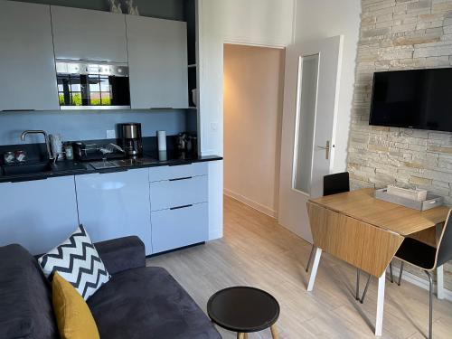 Il dispose d'une cuisine et d'un salon avec un canapé et une table. dans l'établissement le CORDIER Appartement avec terrasse à TROUVILLE SUR MER, à Trouville-sur-Mer