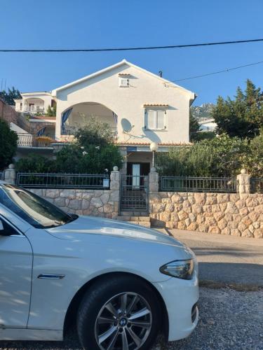 a white car parked in front of a house at Apartman Grospic in Cesarica