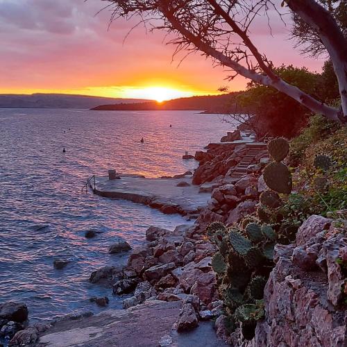a sunset over a body of water with a rocky shore at Apartman Grospic in Cesarica