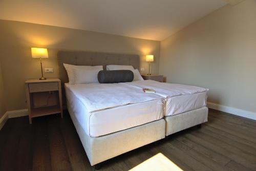 a large white bed in a room with two lamps at Hotel Florian&Godler in Karlovac