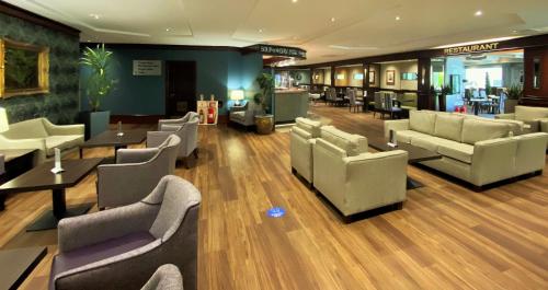 a waiting room with couches and tables and chairs at Normandy Hotel (Near Glasgow Airport) in Paisley