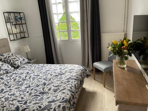 トゥルヴィル・シュル・メールにあるle CORDIER Appartement avec terrasse à TROUVILLE SUR MERのベッドルーム1室(ベッド1台、テーブルの上に花瓶1枚付)
