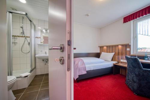 ein Schlafzimmer mit einem Bett und ein Badezimmer mit einer Dusche in der Unterkunft FF&E Hotel Engeln in Papenburg
