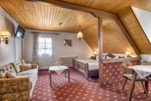 ein Wohnzimmer mit einem Bett und einem Sofa in einem Zimmer in der Unterkunft ZUR TRAUBE Schwarzwaldhotel & Restaurant am Titisee in Titisee-Neustadt