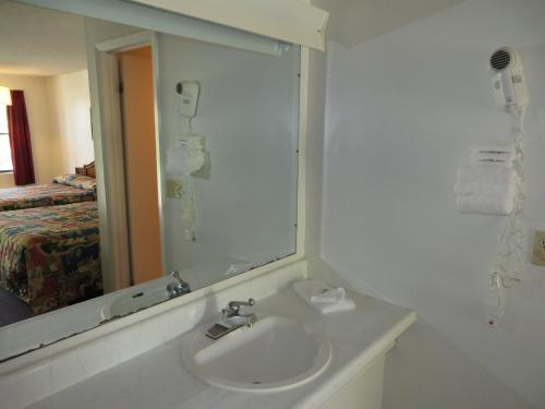 a bathroom with a sink and a mirror and a bed at Scottish Inns Motel - Osage Beach in Osage Beach