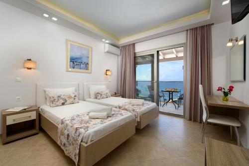 a bedroom with two beds and a desk and a balcony at Villa Boukari Beach in Boukari