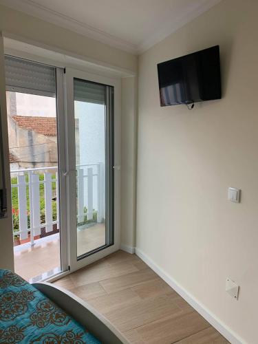 a bedroom with a sliding glass door to a balcony at GuestHouse O Cuco in Praia de Mira