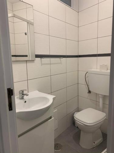 a white bathroom with a toilet and a sink at GuestHouse O Cuco in Praia de Mira