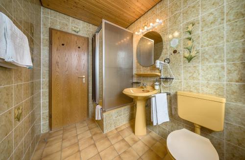 ein Badezimmer mit einem Waschbecken, einem WC und einem Spiegel in der Unterkunft ZUR TRAUBE Schwarzwaldhotel & Restaurant am Titisee in Titisee-Neustadt