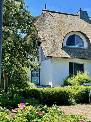a white house with a tile roof and some flowers at Haus Wieck auf dem Darß in Wieck