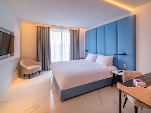 una camera d'albergo con un grande letto e una sedia di Mercure St. Julian's Malta a San Giuliano