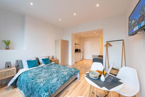 um quarto com uma cama, uma mesa e uma televisão em COSY LOCATION - Confortable, cosy et équipé - Places gratuites à proximité em Anzin