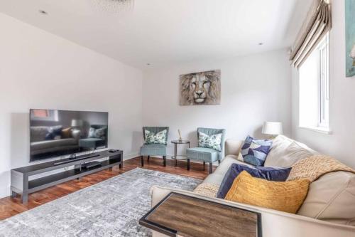 a living room with a couch and a tv at STYLISH 4 BED 2 BATH & PARKING - PINEWOOD HEATHROW - By Tempstay in Slough