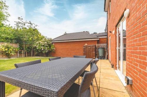 a patio with a table and chairs and a brick building at STYLISH 4 BED 2 BATH & PARKING - PINEWOOD HEATHROW - By Tempstay in Slough