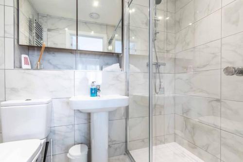 a white bathroom with a sink and a shower at STYLISH 4 BED/2 BATH & PARKING - PINEWOOD/HEATHROW in Slough