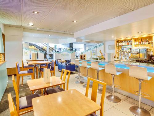 un restaurant avec des tables, des chaises et un comptoir dans l'établissement Novotel Poissy Orgeval, à Orgeval