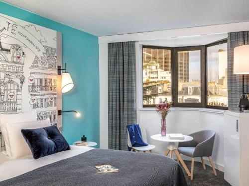sypialnia z łóżkiem, stołem i oknem w obiekcie Hôtel Mercure Paris Centre Gare Montparnasse w Paryżu