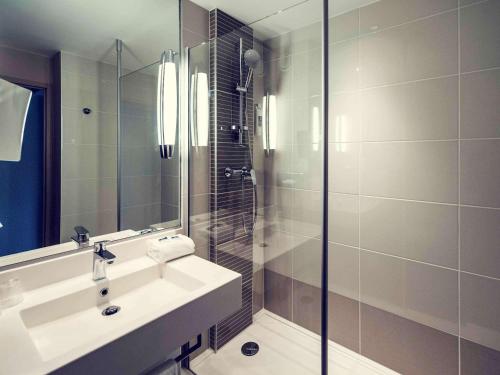 博恩的住宿－博恩中心美居酒店，一间带水槽和玻璃淋浴的浴室