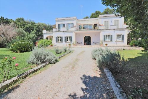 a large white house on a dirt road at Relais Delle Rose in Lecce
