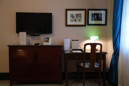a room with a desk with a television and a chair at The Elgin Fairlawn, Kolkata in Kolkata