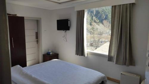 a bedroom with a bed and a window with a television at Gawalmandi Serenity Kalam in Kalām