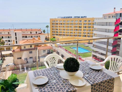 Una mesa con sillas blancas y una vista de un edificio. en Apartment Papa Luna, en Peñíscola