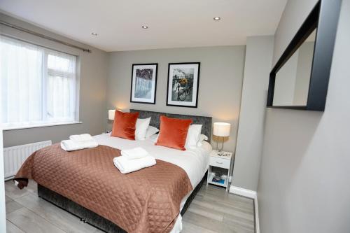 a bedroom with a large bed with orange pillows at FW Haute Apartments at Hillingdon, 3 Bedrooms and 2 Bathrooms Pet-Friendly HOUSE with Garden, with King or Twin beds with FREE WIFI and PARKING in Hillingdon