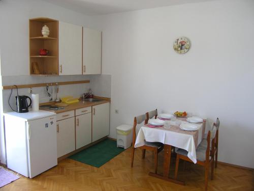 a small kitchen with a table and a white refrigerator at Apartments JADRANKA with magnificent views of the sea - Baska in Baška