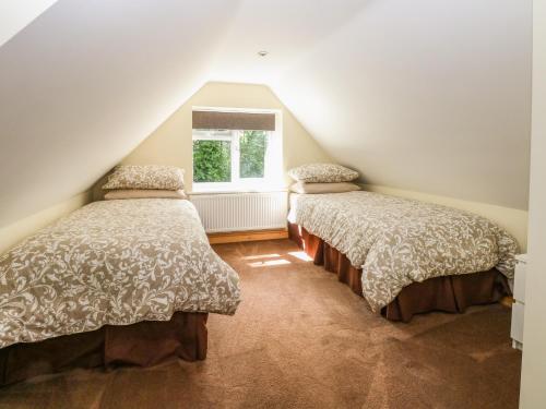 deux lits dans une chambre mansardée avec une fenêtre dans l'établissement Keepers Cottage, à Beeston