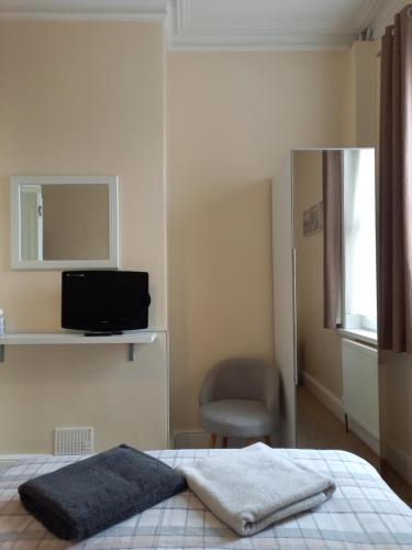 a bedroom with a bed with a chair and a mirror at Crofton Guest House in Weymouth