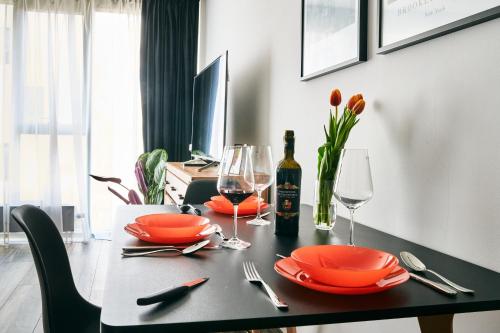 a dining room table with orange plates and wine glasses at EASY RENT Apartments - Crystal, Basen & SPA, Centrum, 24h Check-in in Lublin
