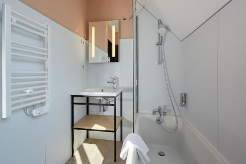 biała łazienka z umywalką i prysznicem w obiekcie Maison Cabotte w mieście Beaune