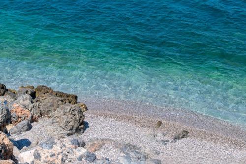 a beach with rocks and the water at Paraskevas Boutique Hotel in Tiros