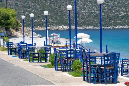 a row of blue chairs and tables on a beach at Paraskevas Boutique Hotel in Tiros