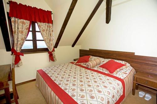 a bedroom with a bed with red pillows and a window at Rooms Bolfan Vinski Vrh in Hrašćina