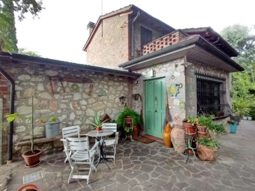 a stone house with a green door and chairs at Tra grilli e cicale in Deruta