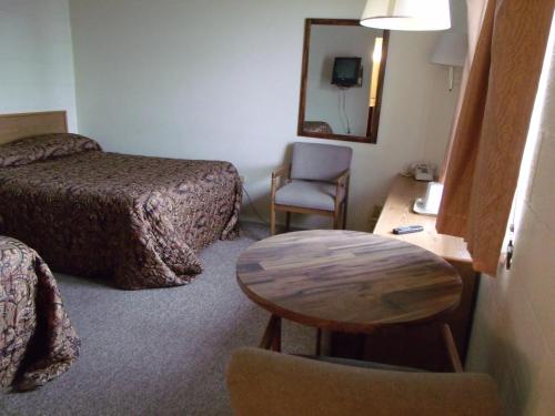 a hotel room with a table and a bed and a chair at Narrow Gauge Railroad Inn in Antonito