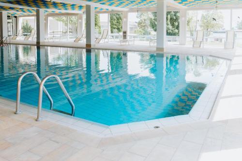 a swimming pool with blue water in a building at HEIMATEL - Suiten, Apartments und Studios in Scheidegg