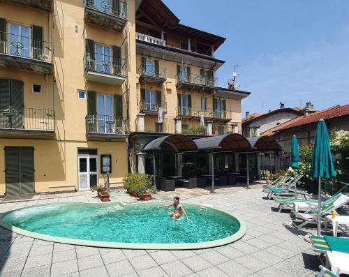 a woman in a swimming pool in front of a building at Hotel Azalea in Baveno