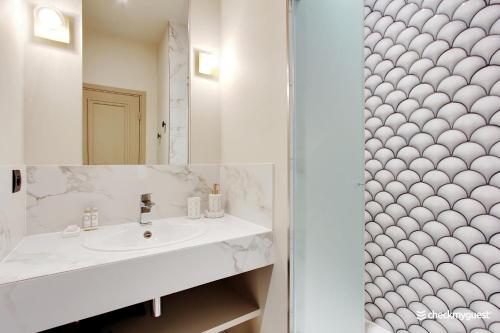 uma casa de banho branca com um lavatório e um chuveiro em CMG - Le Marais / Place des Vosges em Paris