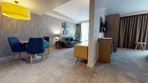 a hotel room with a table and blue chairs at Holiday Inn Manchester - City Centre by IHG in Manchester