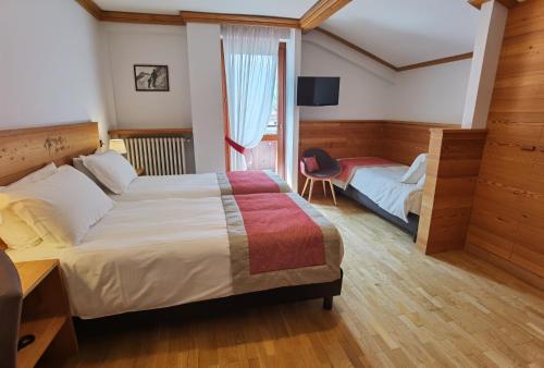 a hotel room with two beds and a window at Hotel Croux in Courmayeur