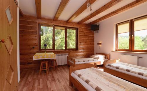 a room with four beds and a table in it at Pensjonat Lesniczówka in Polańczyk