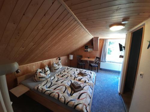 a large bed in a room with a wooden ceiling at FeWo Bockmühle in Hohnstein